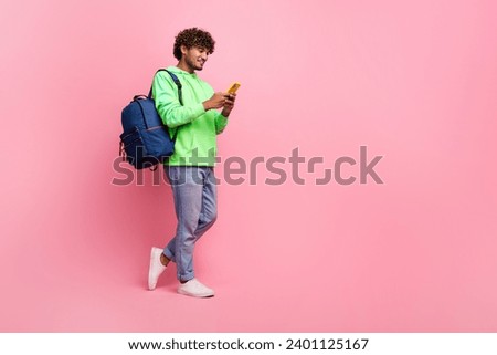 Full body photo of student arabian guy wear green sweatshirt browsing social media in smartphone isolated on pink color background