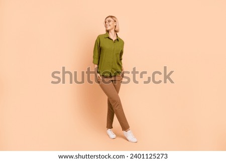 Full size photo of positive pretty girl wear khaki shirt brown trousers look at sale empty space isolated on pastel color background
