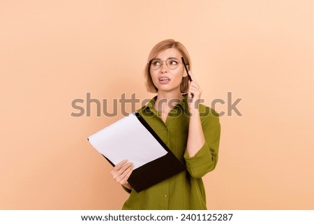 Portrait of minded girl wear khaki shirt in glasses holding clipboard thoughtfully look empty space isolated on pastel color background
