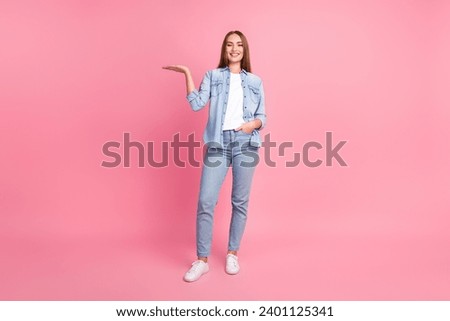Photo portrait of lovely young lady show palm hold empty space dressed stylish denim garment isolated on pink color background