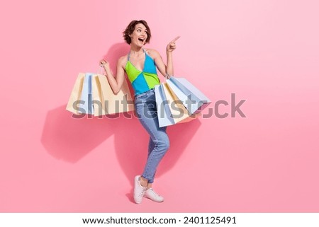 Full length photo of funky woman pointing finger empty space excited recommend brand store in her town isolated over pink color background