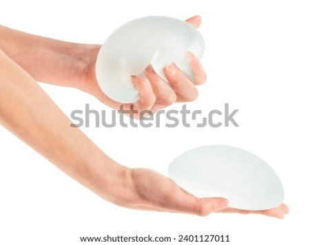 Female squeezing breast implant in hand on white background with clipping path Royalty-Free Stock Photo #2401127011