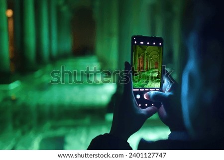 Tourist woman takes a picture on her smartphone in  Basilica Cistern or Yerebatan Sarayi. Selective focus on phone monitor