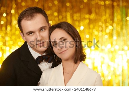 Family evening fashion. Beautiful happy family of spouses posing in festive outfits against a shiny gold foil background. Celebrating Christmas and New Year. Place for text. Royalty-Free Stock Photo #2401148679