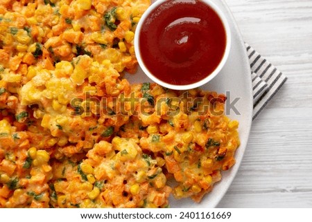 Homemade Carrot Corn Fritters with Ketchup on a Plate, top view. Flat lay, overhead, from above. Royalty-Free Stock Photo #2401161669