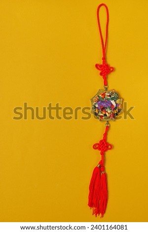 keychain made of red cord with a dragon symbol on a yellow background, copy space