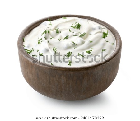 Brown ceramic bowl of fresh sour cream dip sauce with herbs isolated on white background