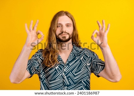 Photo of cool confident man dressed print shirt smiling showing two okey gestures isolated yellow color background