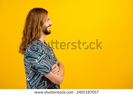 Photo of good mood cheerful man dressed print shirt arms folded looking empty space isolated yellow color background