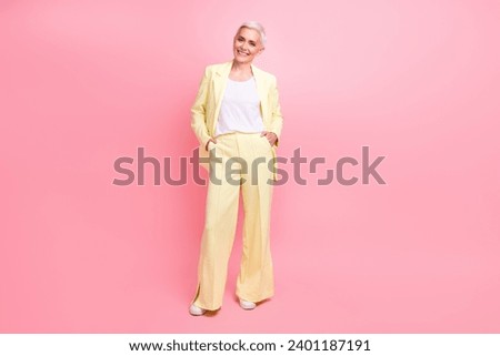 Full size photo of confident successful woman with short hairstyle dressed yellow suit arms in pockets isolated on pink color background