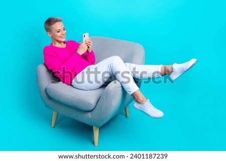 Full size photo of pleasant woman dressed sweater lay on comfortable armchair chatting on smartphone isolated on teal color background
