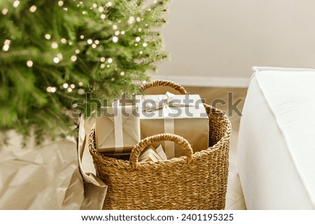 Natural christmas tree pine in wicker bascet with gift boxes in craft paper on wooden floor. Beautiful Christmas tree with gifts and sofa in room, closeup