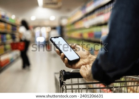 Close up of man using his mobile in supermarket. Shot of an unrecognizable man using a cellphone while shopping at a grocery store.