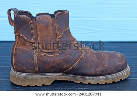 one brown leather old stylish warm winter without laces fashionable with rubber sole comfortable heavy handsome men's boots stands on a black wooden table