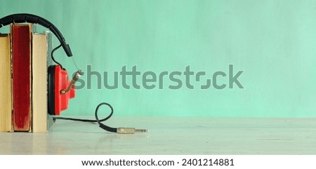 audio book concept with row of books,and vintage headphones, green background, free copy space
