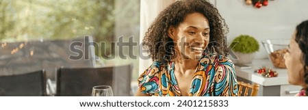 Two smiing female friends talking and drink wine during holiday party at home Royalty-Free Stock Photo #2401215833