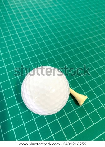 A picture of a golf ball placed on a green background. The material is rubber.