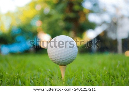 Golf ball set on a background with orange, yellow and green bokeh lights.