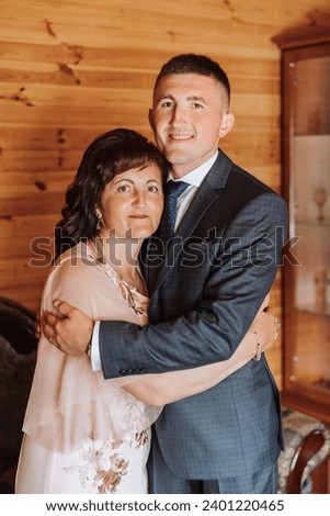 mother helps her adult son prepare for the wedding ceremony. An emotional and touching moment at a wedding. A mother hugs her son