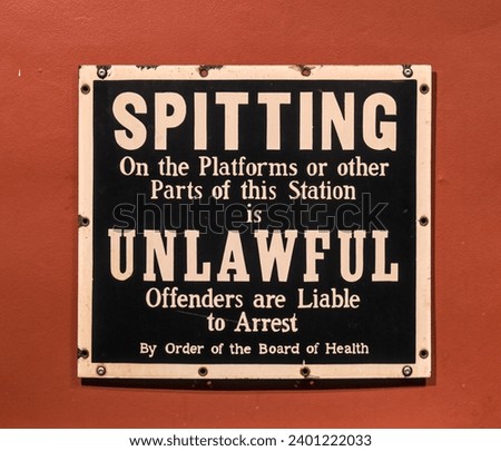 spitting on the platform or other parts the station is unlawful (offenders are liable to arrest) old subway sign on a wall (antique, vintage, nostalgia) regulations rules retro signage