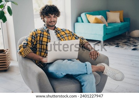 Photo of confident successful man sitting in comfortable armchair dormitory room browsing sms messages indoors