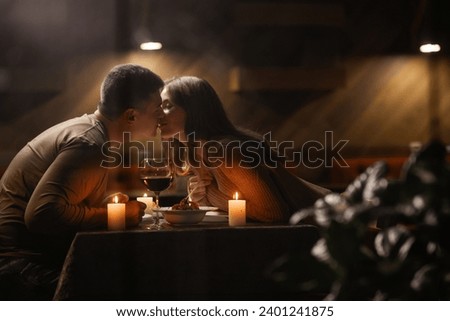 Couple in love celebrating Valentine's day having dinner at home, kissing, view through the window. Copy space Royalty-Free Stock Photo #2401241875
