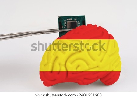 On a white background, a model of the brain with a picture of a flag - Spain, a microcircuit, a processor, is implanted into it. Close-up