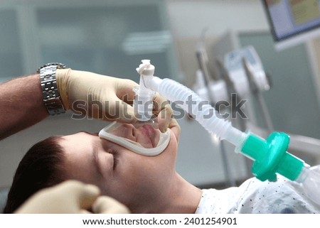A child with an oxygen mask on his face. Preparing child for anesthesia. Dental surgery under general anesthesia. Surgical intervention. Dental treatment under general anesthesia. Side view.