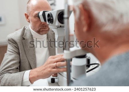 Optometrist using specialized equipment slit-lamp to examine an elderly patient's eyes at the ophthalmology clinic. Close-up photo. Healthcare and medicine concepT: