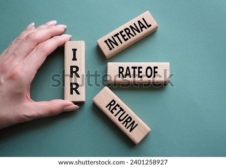 IRR - Internal Rate of Return symbol. Concept word IRR on wooden cubes. Businessman hand. Beautiful grey green background. Business and IRR concept. Copy space.