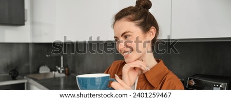 Beautiful young woman with big cup of coffee, smiling and looking happy.