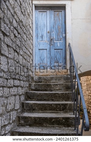 Faded blue wooden door at the end of elevated steps in Europe. Royalty-Free Stock Photo #2401261375