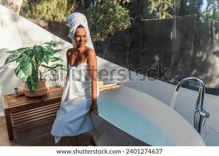 Merry woman waiting for bathtub to be filled with water