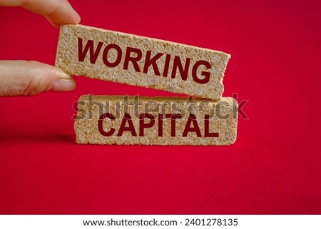 WORKING CAPITAL symbol. Concept words WORKING CAPITAL on brick blocks. Businessman hand. Beautiful red background. Business concept. Copy space.