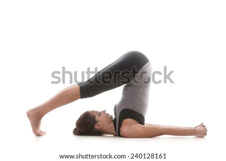Sporty yoga girl on white background in pose halasana (Plow pose)