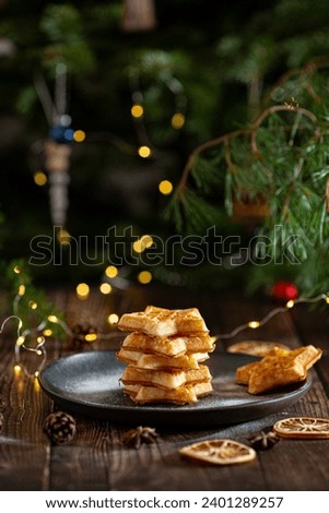 Belgian waffles on the plate with a pine tree on background with Christmas lights