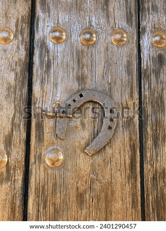 A horseshoe, a symbol of constant luck, hangs on a wooden door, bringing its happy vibrations to the inhabitants of the house.giving away