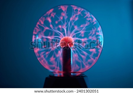 plasma ball. Hands holding plasma light ball. Plasma ball light ray science. Finger touching Plasma ball with smooth magenta blue flames. Electromagnetic Fields in a glass globe. Royalty-Free Stock Photo #2401302051