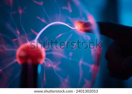 plasma ball. Hands holding plasma light ball. Plasma ball light ray science. Finger touching Plasma ball with smooth magenta blue flames. Electromagnetic Fields in a glass globe. Royalty-Free Stock Photo #2401302053