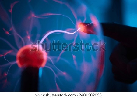 plasma ball. Hands holding plasma light ball. Plasma ball light ray science. Finger touching Plasma ball with smooth magenta blue flames. Electromagnetic Fields in a glass globe. Royalty-Free Stock Photo #2401302055