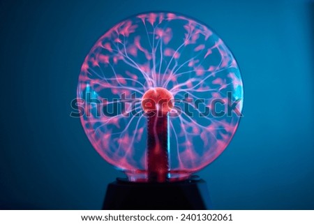 plasma ball. Hands holding plasma light ball. Plasma ball light ray science. Finger touching Plasma ball with smooth magenta blue flames. Electromagnetic Fields in a glass globe. Royalty-Free Stock Photo #2401302061