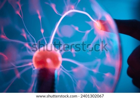plasma ball. Hands holding plasma light ball. Plasma ball light ray science. Finger touching Plasma ball with smooth magenta blue flames. Electromagnetic Fields in a glass globe. Royalty-Free Stock Photo #2401302067