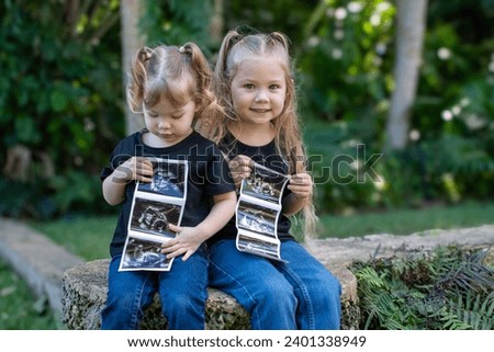 Pregnancy announcement by siblings. Social media pregnancy announcement. Big sister. Third child in a family. Two kids holding sonogram of a new baby 