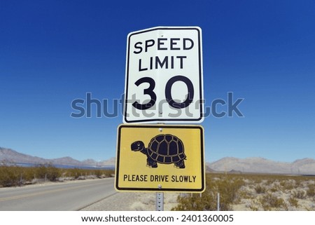 Road sign in a desert area indicating a speed limit of 30 mph warning for desert tortoises potentially crossing the road. Royalty-Free Stock Photo #2401360005