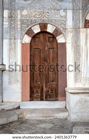 Wooden doors of an Arab mosque against a background of a marble wall. Template for design. Royalty-Free Stock Photo #2401363779