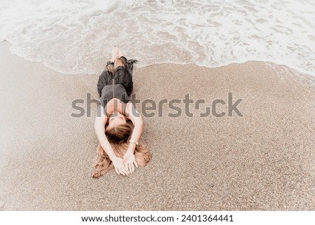 Woman summer travel sea. Happy tourist in black dress enjoy taking picture outdoors for memories. Woman traveler posing on sea beach surrounded by volcanic mountains, sharing travel adventure journey