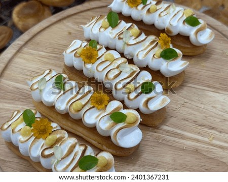 Lemon Meringue Tart from the oven filled with vanilla cream. Dessert on a white plate.  Yellow flower background. Menu coffee shop.  Closeup shot of little sweet decorative. Free space for text.