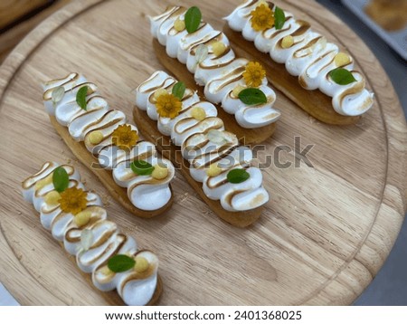Lemon Meringue Tart from the oven filled with vanilla cream. Dessert on a white plate.  Yellow flower background. Menu coffee shop.  Closeup shot of little sweet decorative. Free space for text.