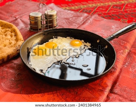 photo side view of fried eggs with bread in a pan on red carpet