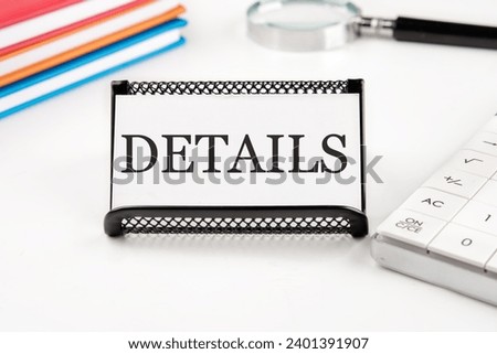 DETAILS text on a business card next to office supplies on a white background